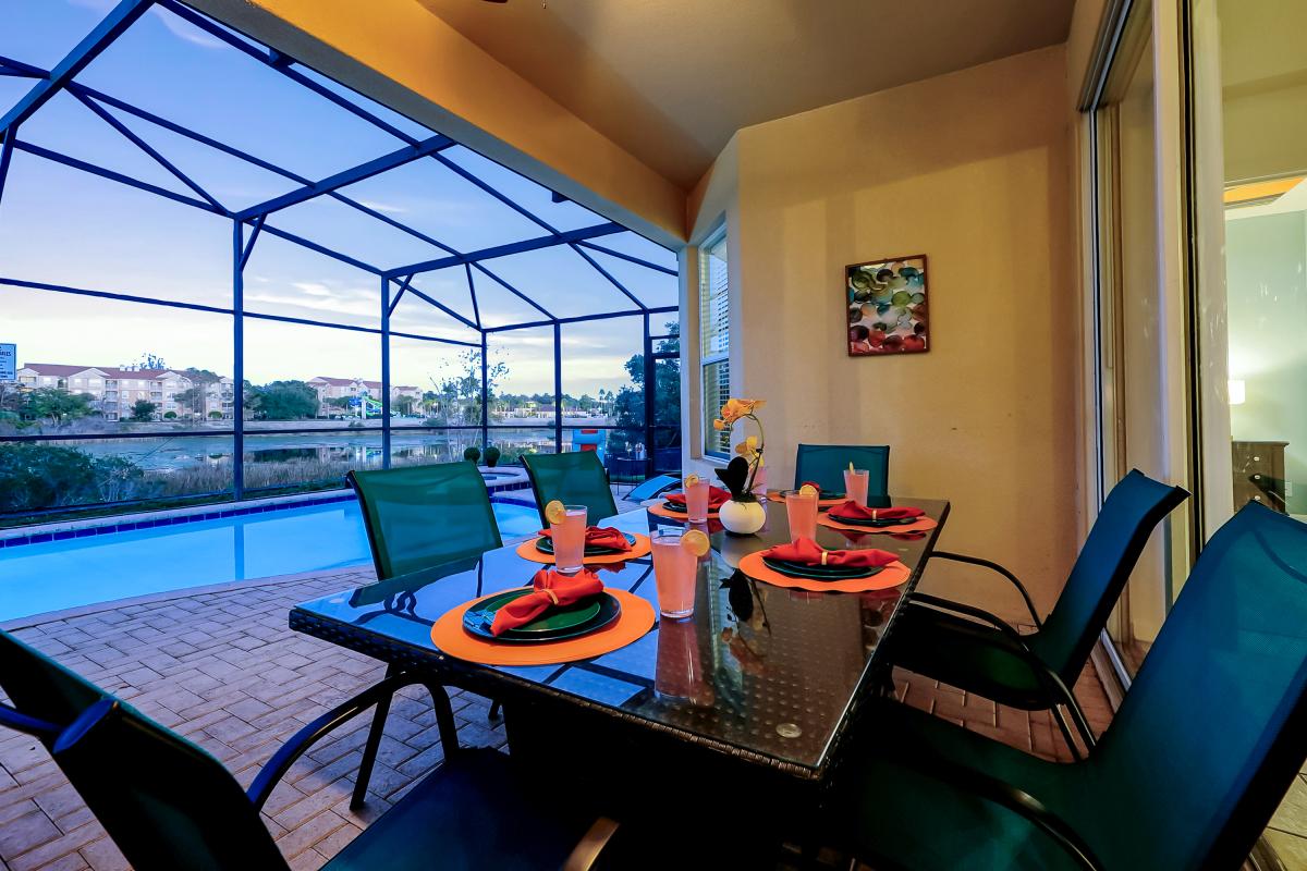 Covered screened lanai with outdoor dining, private pool, and peaceful lake views?perfect day to nig